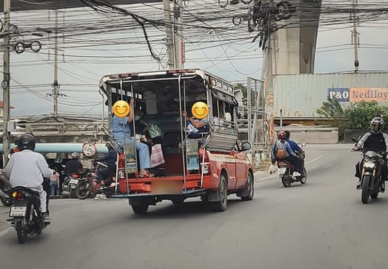 สองแถวสีส้มแดงบนถนน ใต้สายไฟและทางยกระดับ